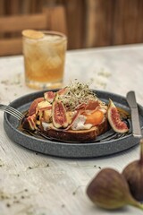 Closeup of fig and jam toast on a rustic table with golden drink