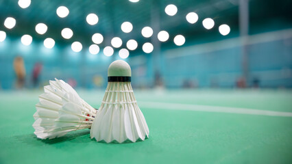Badminton shuttlecock on the floor with blur badminton indoor sport game court background with...