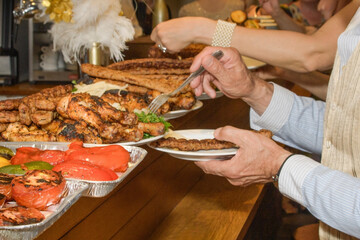 Hands of an elderly man choosing meat snacks in a restaurant buffet