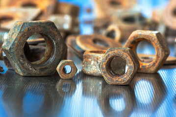 Rusted component, threaded nuts on metal workshop table