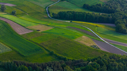 Colorful farm fields with crop on rolling hills, aerial drone view. Polish countryside