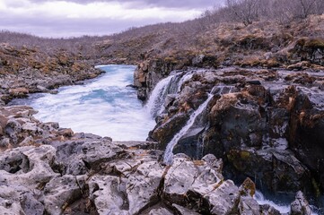 Majestic mountain range featuring a spectacular waterfall cascading down its rocky face in Iceland