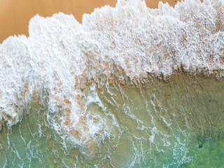 Top view beach with waves crashing on sandy shore,Beautiful waves sea surface in summer seascape background,Amazing beach colorful water background
