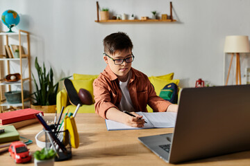 A adorable boy with Down syndrome focused on his laptop at home.