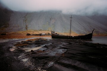 the boats on the wet beach are in the water near the shore