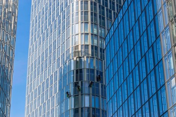 Obraz premium Low angle shot of window cleaners working on skyscrapers in the daylight