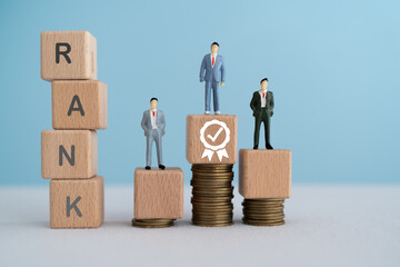 RANK text on wooden cube block and miniature of businessman stand on wooden cube block over stack...
