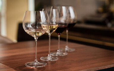 Wine glasses in a row. Glasses with different wines on wooden table. Nightlife, celebration and entertainment concept.