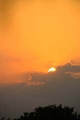 the setting sun is almost above the clouds that are almost yellow