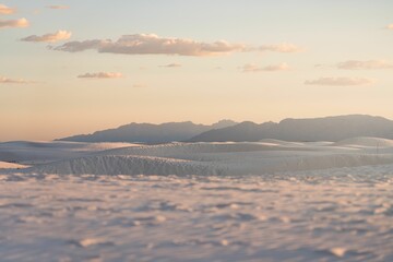 Desert landscape featuring a sandy expanse with a serene sunset glow shimmering across the surface