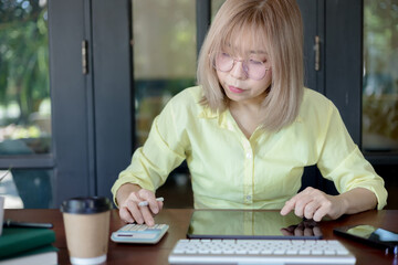 Business woman using calculator and writing make note with calculate. Woman working at office with...