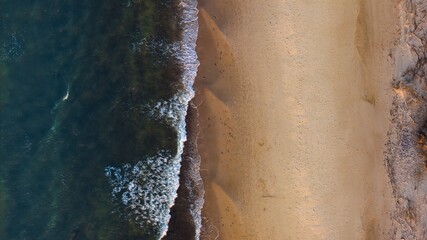 Golden hour aerial: Sandy beach, gently rolling waves in Sopot, Poland.