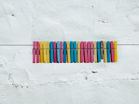 Colorful Clothespins Lined Up on a Wire Against a White Wall