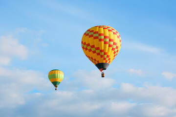 Two hot air balloons with tourists against a blue sky. Beautiful view of colourful hot air balloons from below