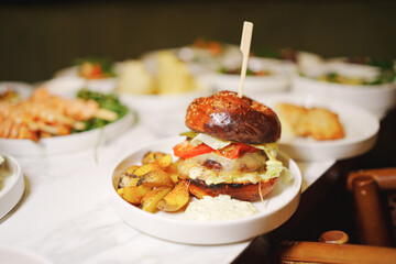 A classic American dish of a hamburger and french fries served on a plate with tableware, a staple food in Western cuisine, made with ingredients like beef, potatoes, and condiments