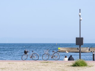 Couple sitting on the beach next to parked bicycles on a sunny day
