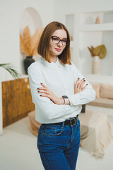 Cute woman in glasses in open space, coworking office, relaxing relaxing, working remotely online, wearing white t-shirt and jeans