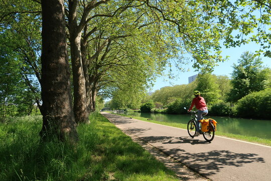 Cyclotourisme dans la campagne, sur une piste cyclable bord&eacute;e d&rsquo;arbres, au bord du canal de Bourgogne &agrave; Dijon, en C&ocirc;te d&rsquo;Or, paysage de nature avec une femme cycliste sur un v&eacute;lo de randonn&eacute;e (France)