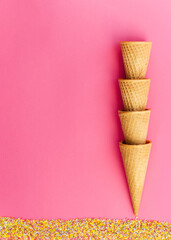 Ice cream cones with colorful sprinkles on pink background. Close-up, vibrant colors.