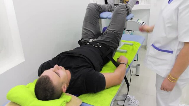 Footage of a patient lying on his back at the back stretching therapy at a physiotherapist