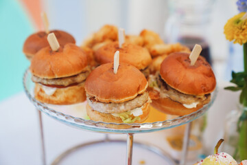 A plate of burgers on the banquet table. Simple and delicious food for a children's or family party. Fast food.