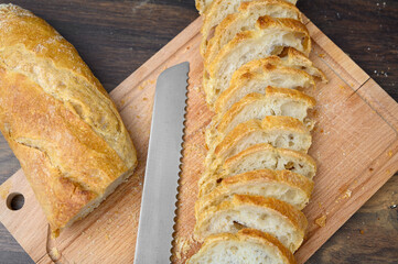 Długa bułka typu bagietka na desce do krojenia na drewnianym blacie kuchennym 