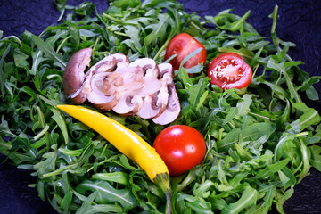 Ingredients for salad. Greens and mushrooms for preparing vegetarian food on a black background