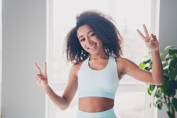 Photo of nice fit young woman demonstrate v-sign sportswear training home gym indoors