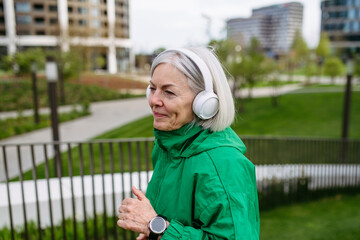 Mature woman listening music while running. Exercising after work for good mental health, physical health, relieving stress and boost mood.