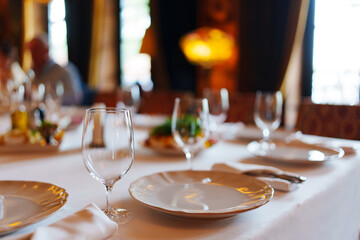 An empty wine glass and plates on a table served for a banquet. 