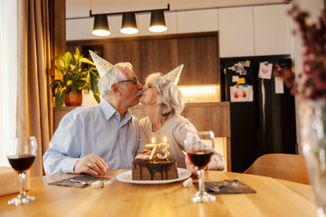 Affectionate senior couple kissing and celebrating birthday at home.