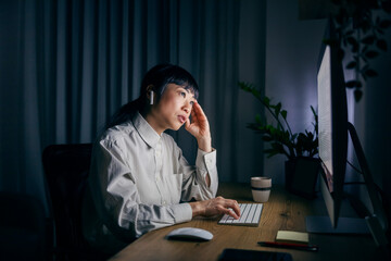 A middle aged japanese businesswoman sitting at home office at night and working on her report.