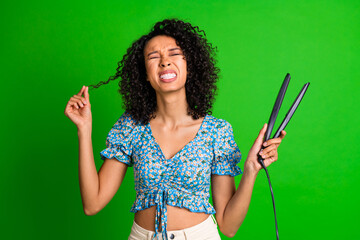 Photo of nice young woman bad mood split ends hair straightener wear top isolated on green color...