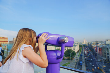 a teenage girl looks into the Binoscope from the observation deck at a height. 