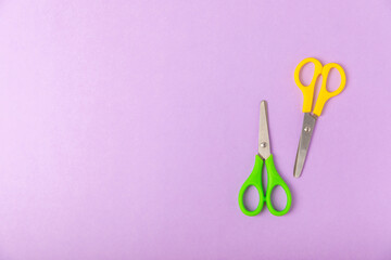 Bright children's scissors on a colored paper background. Stationery. Goods for school. Place for...