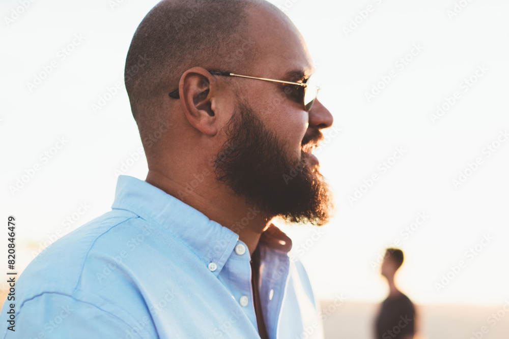 Poster bearded man sending text message via mobile telephone chatting online while enjoying summer evening,