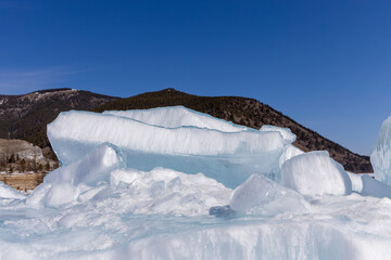 Winter natural background with fragments of blue ice and heaps of pieces of ice floes on Lake...