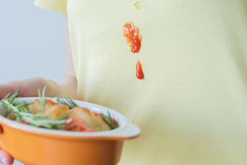 Close up drops tomato sauce or ketchup on yellow clothes.