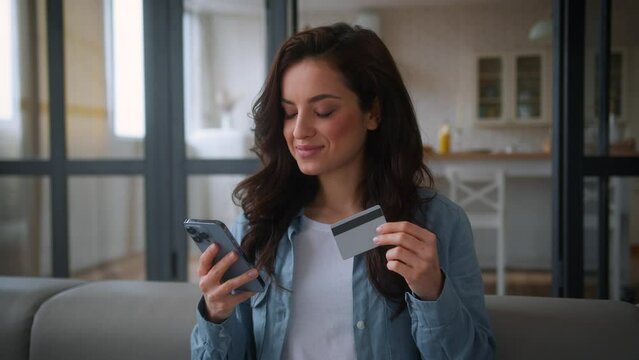 Smiling Caucasian woman buyer client girl female buying shopping online at home mobile phone bank app internet store shop smartphone buy order food delivery booking credit card payment at couch sofa