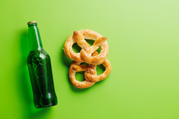 Beer bottle and pretzels on green background