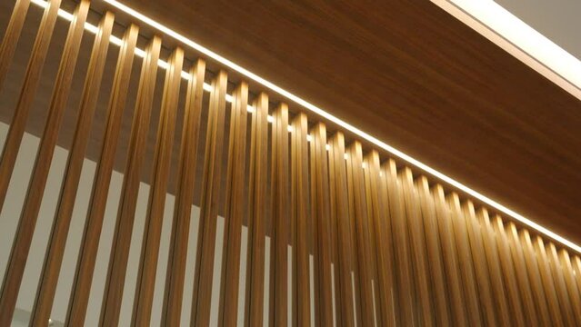 Modern interior wall design featuring vertical wooden slats with integrated lighting. Warm glow highlighting natural pattern and creating elegant atmosphere indoors