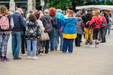 Crowd of unrecognizable people waiting in line on street, queue of people, back view