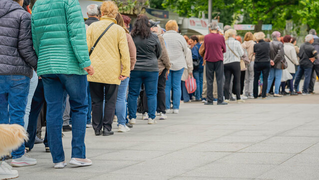 Long queue of people in street, back view