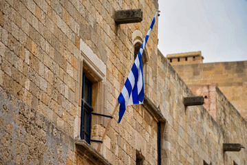 The Greek flag hangs on the wall of the building.