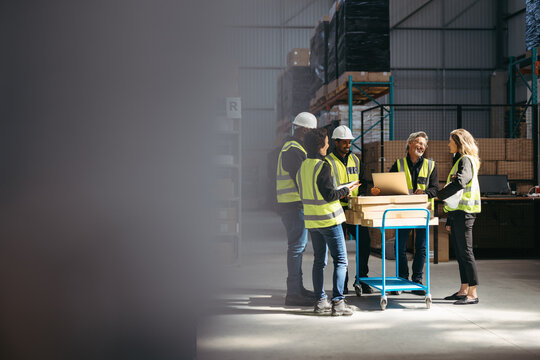 Group of happy warehouse employees having a meeting together
