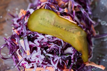 Purple cabbage salad with carrots. Decorated with salted or pickled cucumber