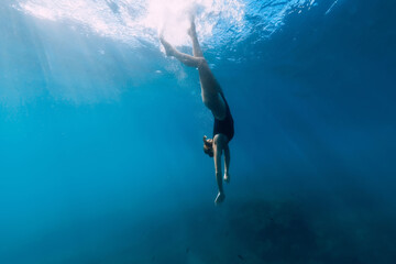 Woman dive to the sea bottom in blue ocean. Free diving with beautiful girl in ocean
