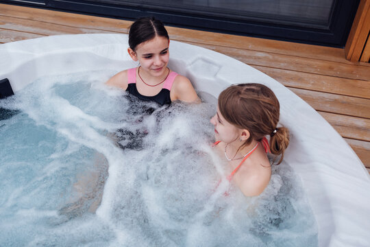 Two cute teenage girls in swimsuits spending time in the jacuzzi.