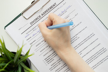 Divorce agreement, hand fills out a document, legal proceedings, marriage dissolution, partner signature, marriage dissolution