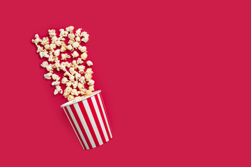 Popcorn bucket, cinema movie snack, salted crunchy treat cardboard,red background, copy space